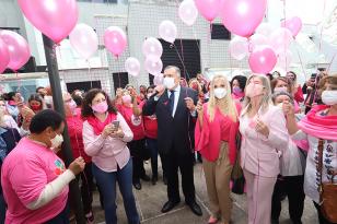 Lançamento da campanha Outubro Rosa. Várias pessoas usando roupas cor-de -rosa  seguram balões rosas em dois tons diferentes. 