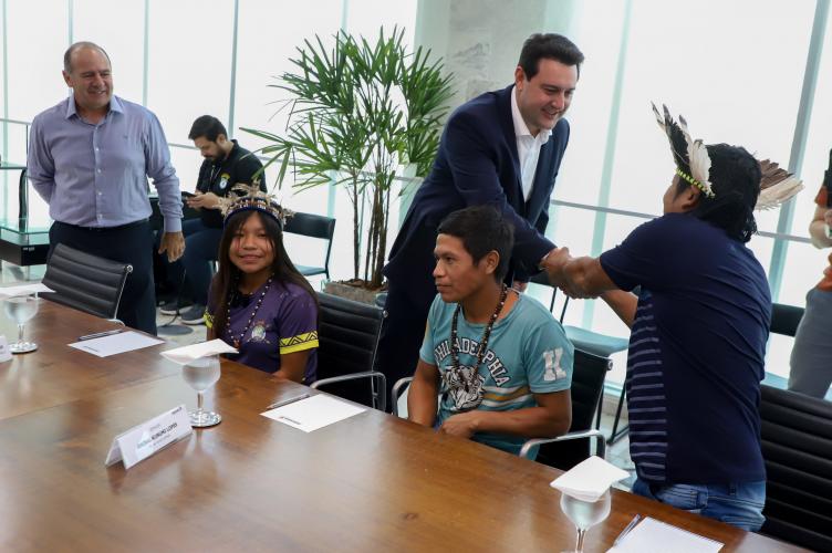 A aluna Larissa Takua Poty Ju Lopes, de 15 anos, será a primeira aluna indígena a participar do Ganhando o Mundo, programa de intercâmbio do Governo do Estado. A estudante da terra indígena Tekoha Añatete, de Diamante do Oeste, no Oeste do Estado, foi um dos alunos selecionados para passar um semestre letivo de 2025 em um país estrangeiro. Ela foi recebida nesta segunda-feira (10) pelo governador Carlos Massa Ratinho Junior no Palácio Iguaçu.
